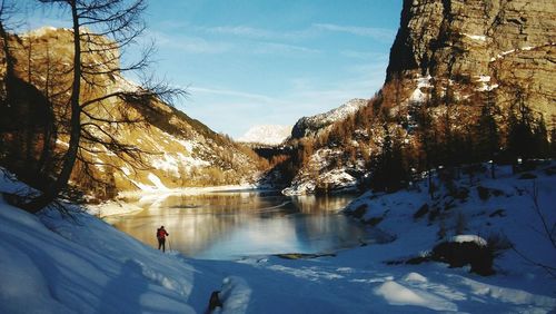 Hiker by lake in valley during winter