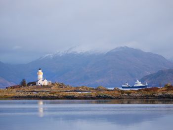 Lighthouse on isle of ship at rocky island, mountains in background. isle of skye, scotland, uk