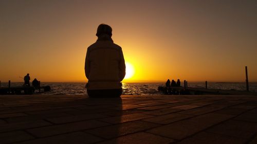 Silhouette people on beach against clear sky during sunset