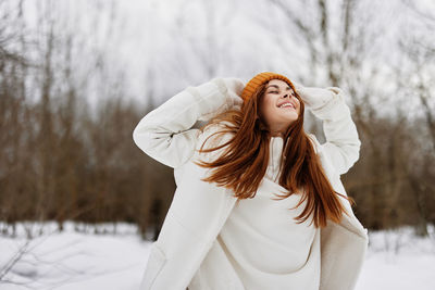 Cheerful woman standing on snow covered land during winter