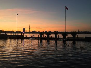 Silhouette wooden posts in lake against sky during sunset