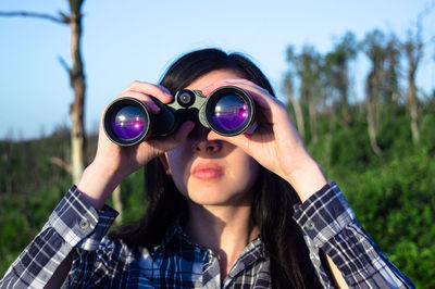 Woman looking through binoculars on sunny day