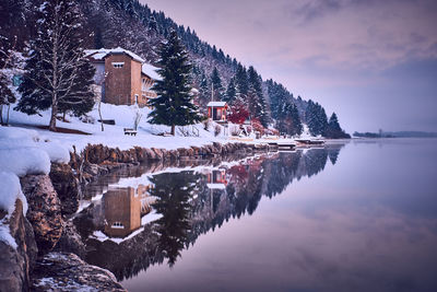 Buildings by lake against sky during winter