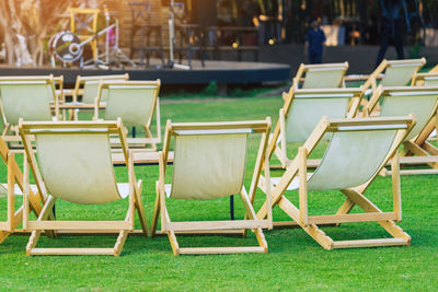 Many white deck chairs with tables for dinner in lawn is surrounded by shady green grass 