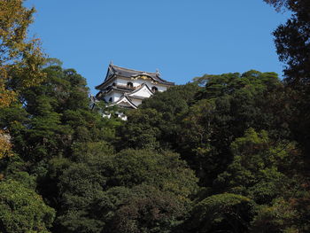 Low angle view of trees and building against clear sky