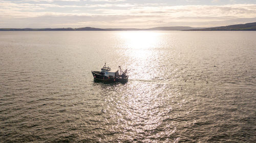 Boat sailing on sea against sky during sunset