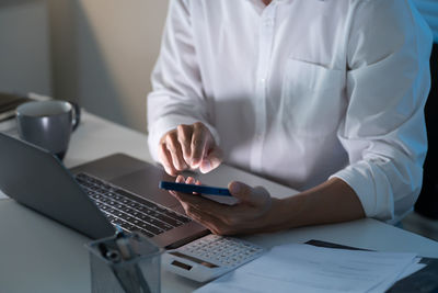 Midsection of man using laptop on table