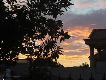 Silhouette trees and buildings against sky during sunset