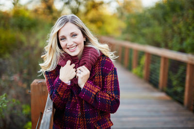 Portrait of smiling young woman standing in park during autumn