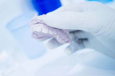 Cropped hand of person holding dental mold