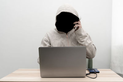 Rear view of man using mobile phone while sitting on table