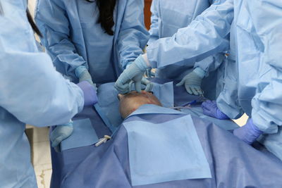 Midsection of doctors performing operation on patient