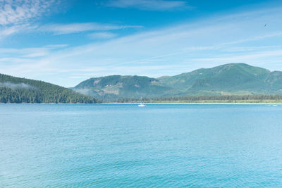 Scenic view of sea and mountains against blue sky