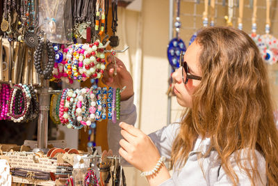 Close-up of girl wearing sunglasses buying bracelets in market