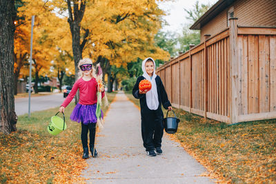 Full length of smiling sibling walking on footpath