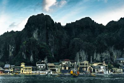 Boats moored on river by mountains against sky