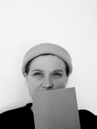 Portrait of young woman wearing hat against white background