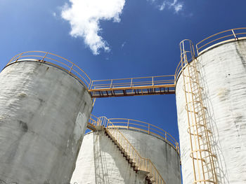 Low angle view of storage tanks against sky