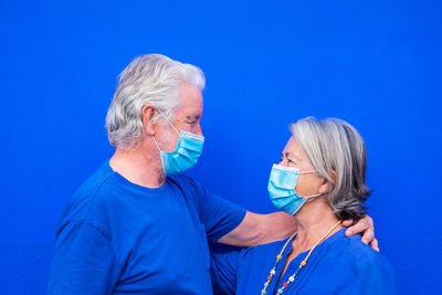 Smiling senior couple standing against blue background