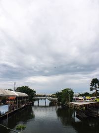 Bridge over river by buildings against sky