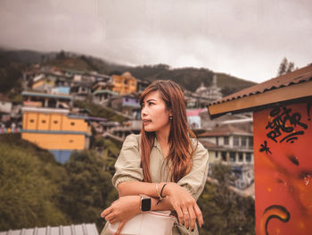 Young woman looking at camera against sky