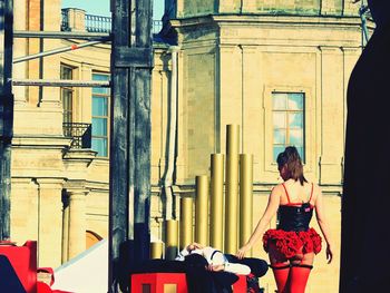 Street performers against buildings in city on sunny day