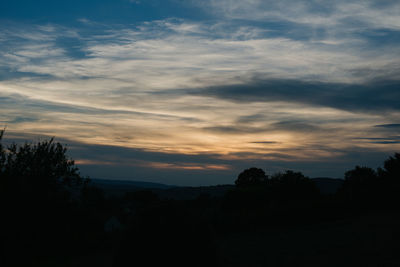 Silhouette trees on field against sky at sunset