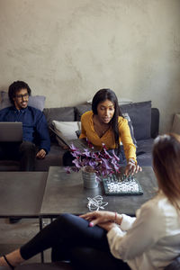 Female professionals playing chess near businessman at creative office