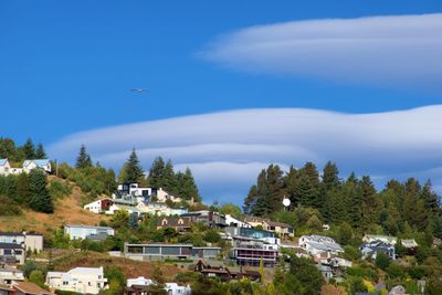 Low angle view of houses on mountain against blue sky during sunny day