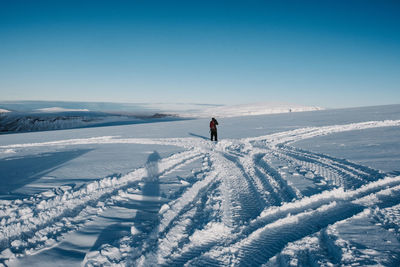 Person on snow covered land against sky