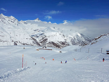 People skiing on snowcapped mountain against sky