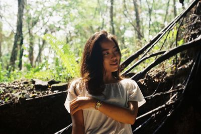 Young woman standing against trees in forest