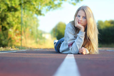 Portrait of young woman sitting on road