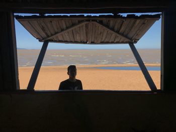 Rear view of woman sitting on beach