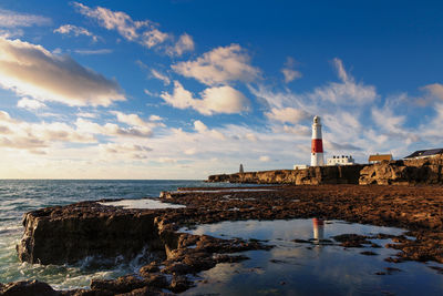 View of lighthouse by sea against sky