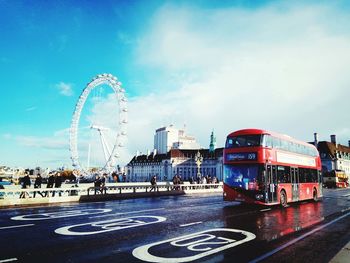 Ferris wheel by road against sky in city