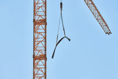 Low angle view of crane against clear blue sky