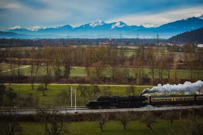 Scenic view of train by mountains against sky