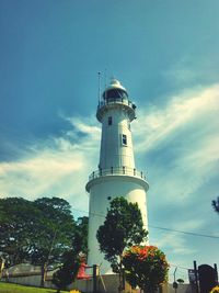 Low angle view of lighthouse by building against sky