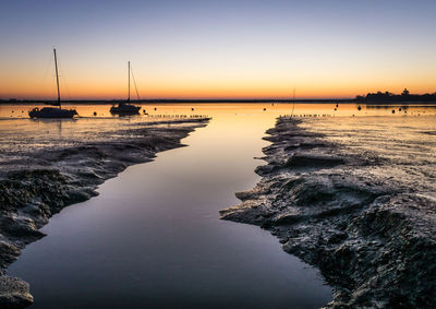 Sailboats on sea against sky during sunset