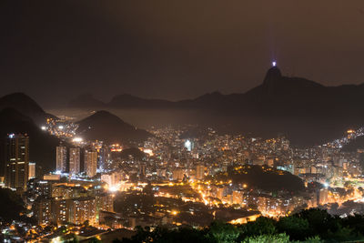 Illuminated cityscape at harbor against sky at night