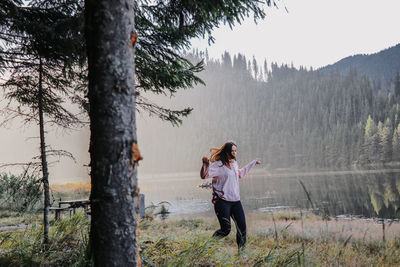 Full length of woman standing on tree trunk