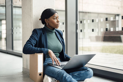 Thoughtful businesswoman with laptop sitting at office