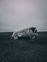 Abandoned airplane on sea shore against sky