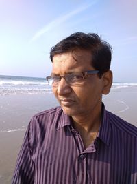 Portrait of mature man at beach against sky