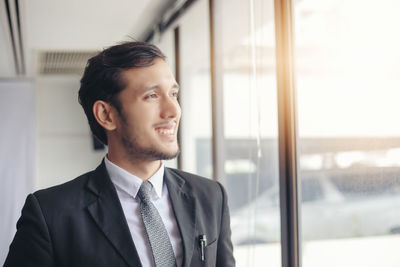 Smiling businessman looking though window in office