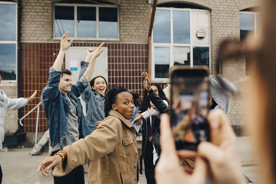 Happy multiracial young friends dancing on street