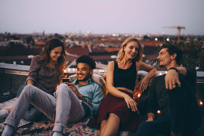 Couples relaxing together on terrace in city during rooftop party