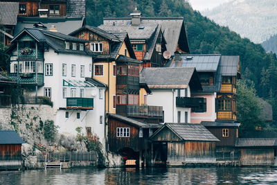 Houses by river against buildings in city