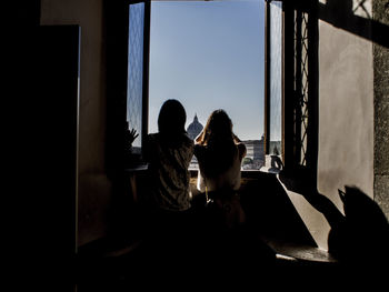Rear view of couple sitting on window